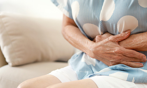 Mujer tocándose la barriga dolorida