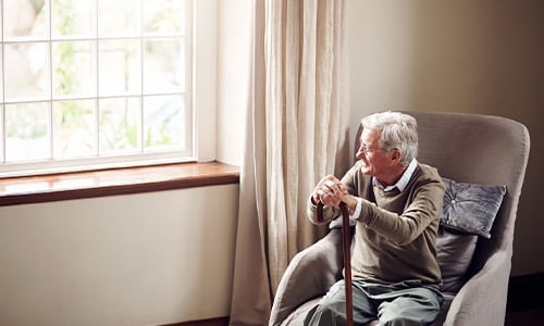 Abuelo sentado en un sillón mirando a través de la ventana