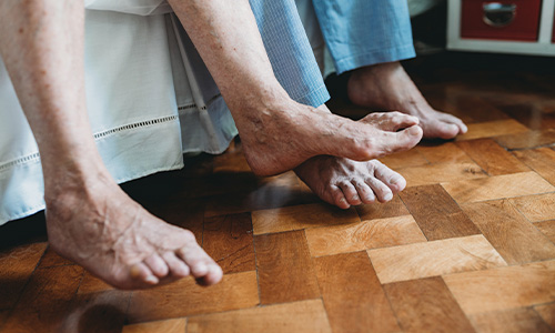 Personas mayores con los pies descalzos al borde de la cama