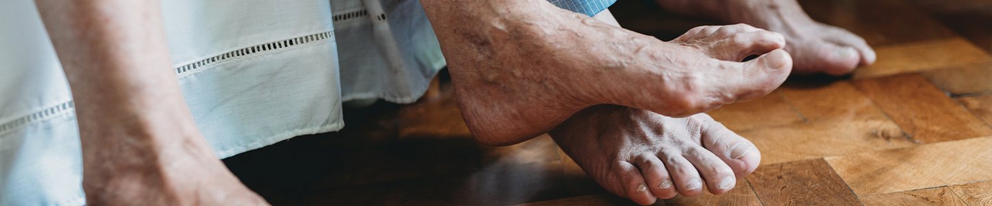 Personas mayores con los pies descalzos en el borde de la cama
