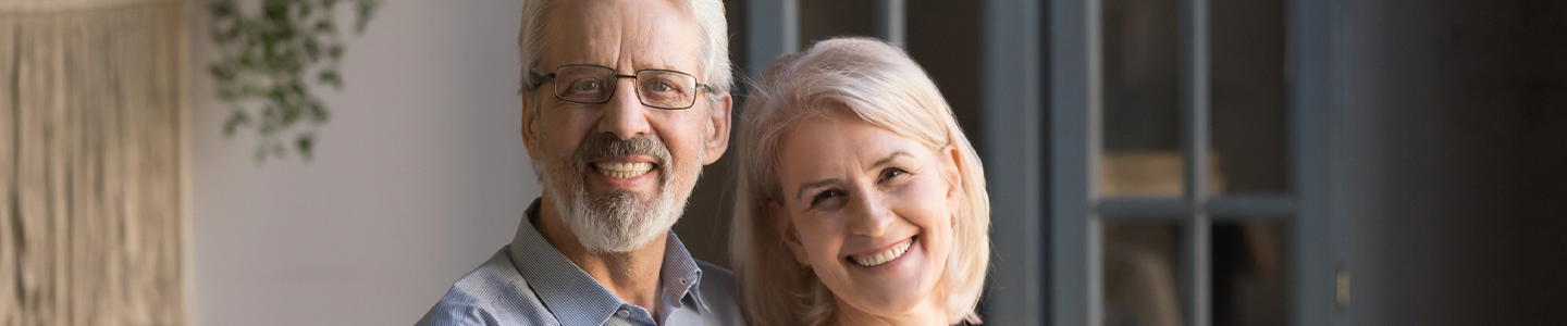 Hombre y mujer de mayor edad se abrazan sonriendo 