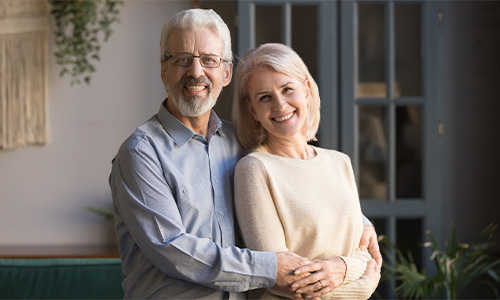 Hombre y mujer de mayor edad se abrazan sonriendo 