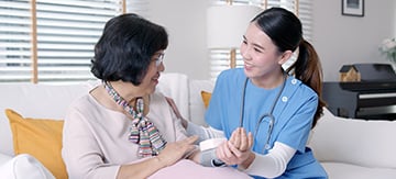 Mujer mayor tomándose la presión con la ayuda de una enfermera. Es una práctica habitual y recomendable para asegurarse de tener el colesterol normal en mujeres.