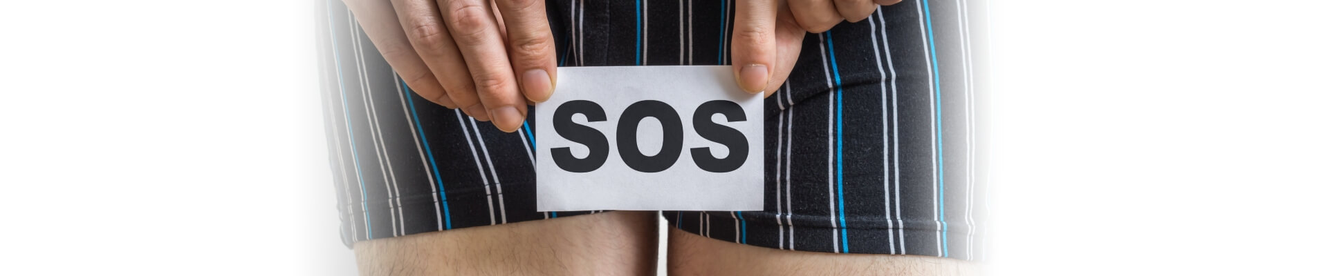 Hombre mayor con un cartel de SOS en frente de sus calzoncillos, ya que sufre dolores por culpa de la irritación del pañal.