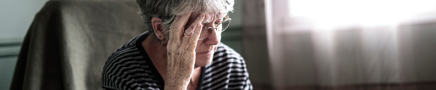 Mujer anciana que sufre depresión en sus años más maduros. Se encuentra sentada en una butaca poniendo su mano en la cabeza ya que sobre piensa mucho algúnos temas que la preocupan.