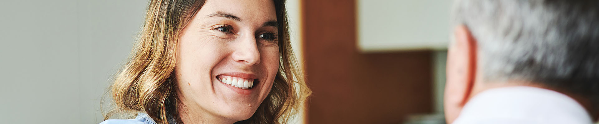 Enfermera explicando a un señor mayor al cual coje por el hombro mientras sonrie, las dudas que tiene sobre las diferencias entre las residencias públicas y privadas