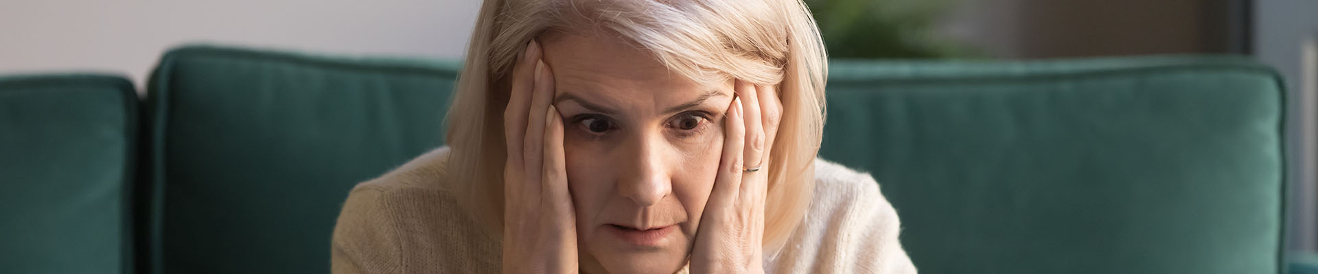 Mujer en edad de jubilarse mirando en el ordenador que requisitos le hacen falta para jubilarse y haciendo cara de sorprendida ya que la jubilación sin cotizar los últimos años es complicada.