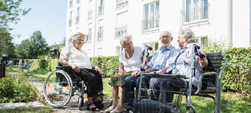 Gente mayor sentados al sol, en un banco, disfrutando del jardín de una de las mejores residencias de España